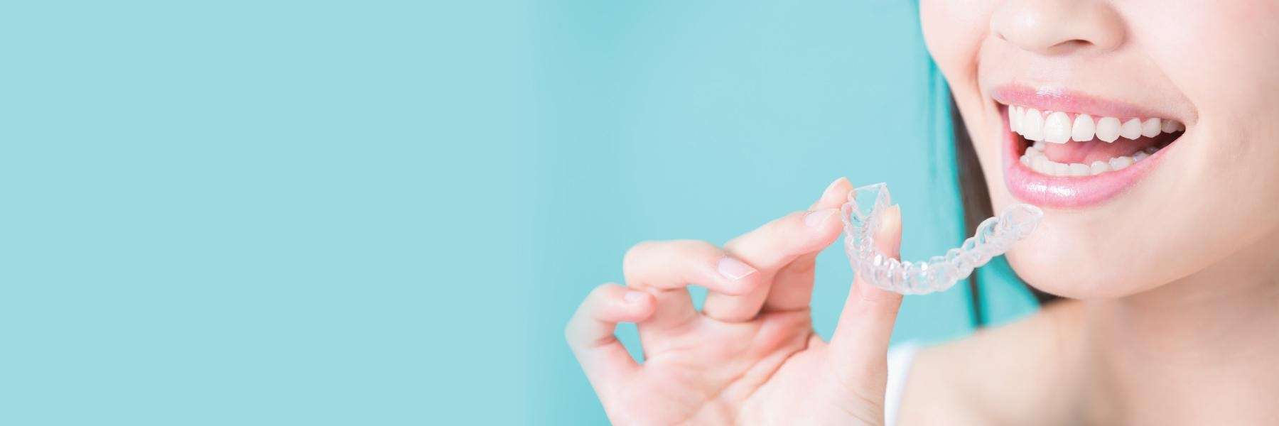 A woman holding her clear Invisalign with her one hand in Rutland